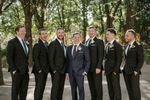 Groom and his groomsmen smiling in a garden while waiting for the wedding ceremony at Marie Gabrielle