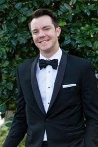 Smiling groom in a black tux looking at the camera