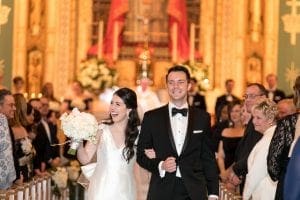 Bride and groom smiling and laughing as they leave the chapel and guests look on