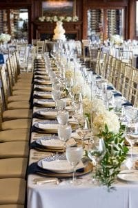  View of the room with guest tables and head tables in the reception room with the cake in the background