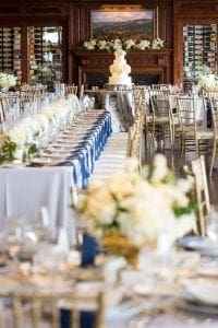 View of the room with guest tables and head tables in the reception room with the cake in the background