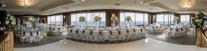 Panoramic view of the room with guest tables and head table along with the white dance floor on the reception room