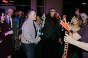 Guest dancing with an air guitar as wedding guests laugh and look on on the dance floor at The Bowden