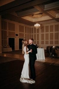 Bride and groom smiling with their arms around each other as they have their private last dance in the reception room at The Bowden