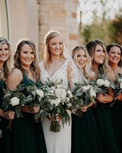 Bride and bridesmaids smiling at the camera holding their bouquets