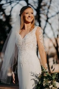 Bride smiling into the distance in her wedding gown and veil holding her bridal bouquet