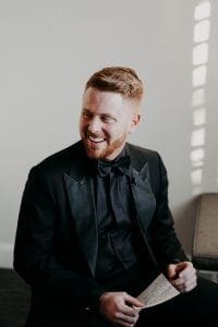 Groom smiling as he reads a letter the bride wrote him on their wedding day
