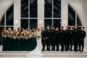  Bride and groom kissing as their bridal party watches on smilingly in the chapel at The Bowden