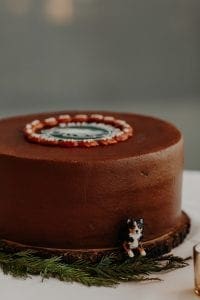  Round grooms cake made of chocolate with a little dog figurine on one side