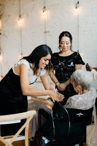 Planner helping a grandmother put on a wrist corsage before the wedding ceremony