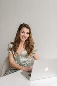 Smiling woman typing into a macbook laptop