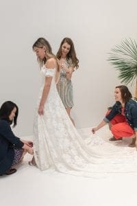 Three women helping a bride in her wedding dress