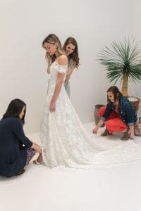 Three women helping a bride in her wedding dress