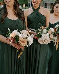 Three bridesmaids in emerald green carrying their bouquets