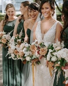  Bride and her bridesmaids on their way to the ceremony laughing and carrying their bouquets The bridesmaids are in emerald green