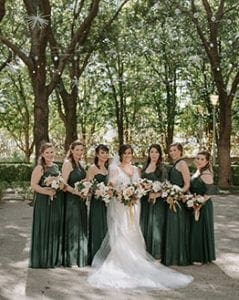  Bride and her bridesmaids wearing emerald green carrying their bouquets smiling at the camera