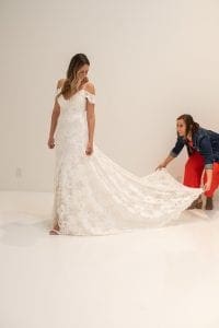 Woman helping a smiling bride fluff out her wedding dress
