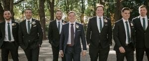 Groom and his groomsmen in their tuxes walking towards the ceremony smiling