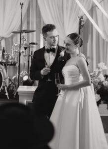Bride and groom in wedding attire toasting with champagne glasses at their reception