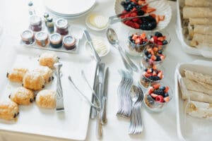 Buffet table with croissants jam jars and plates plus fruit and granola yogurt cups ready for self serve